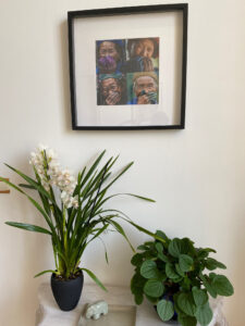 Deux plantes vertes en pot et un cadre artistique sur un mur blanc dans l’entrée du Château Papounan, chambre d’hôtes de charme à Saint-Estèphe, Médoc.
